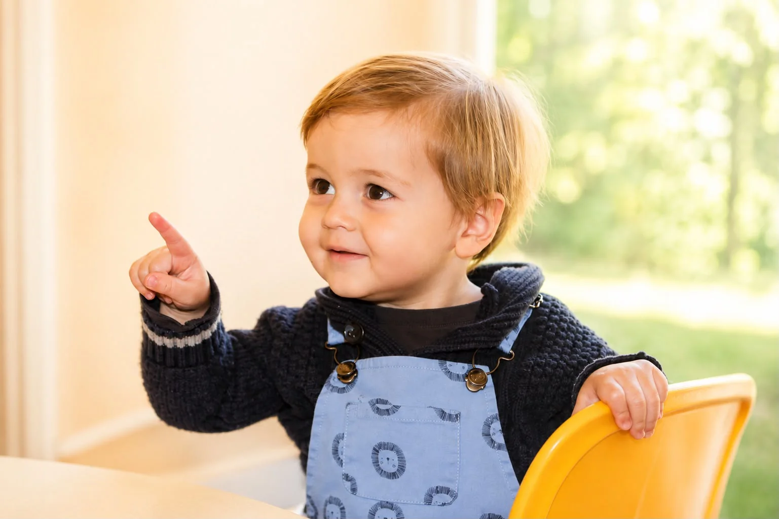 Niño sonriente sentado en una silla amarilla, señalando hacia un lado