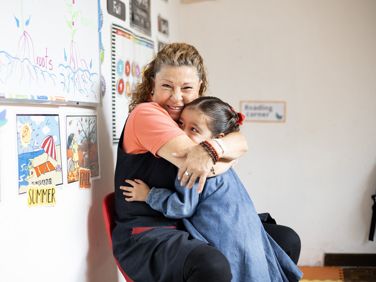 Maestra de Piruli abrazando a una niña en el salón
