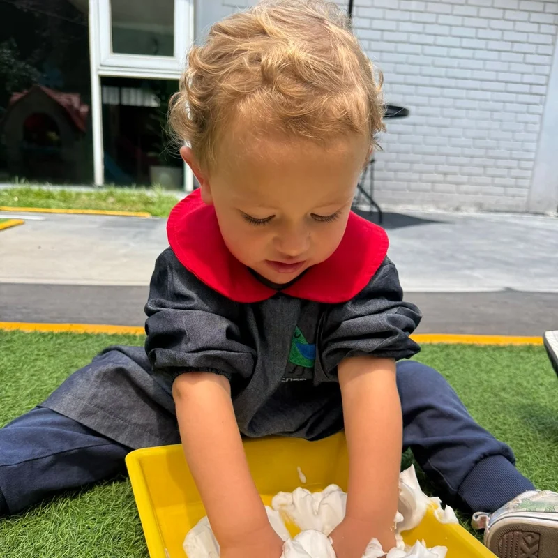 Peque de Pirulí jugando con espuma en una charola amarilla