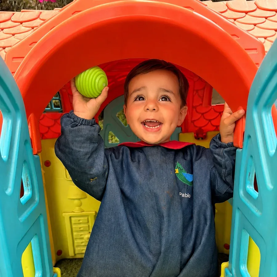 Niño sonriendo dentro de una casita de juegos