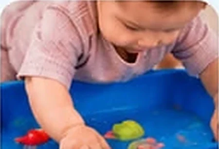 Bebé tocando juguetes en una tina de agua